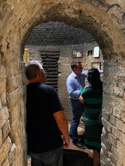 Grupo de visitantes dentro do primeiro forno de tijolos, observando fotografias históricas