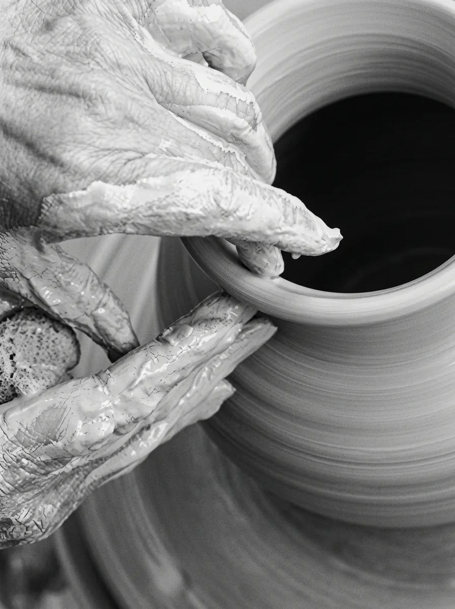 Mãos moldando uma peça de porcelana em um torno