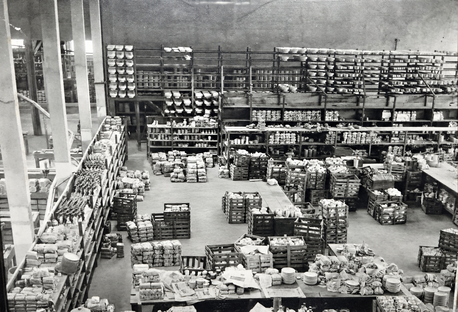 Fotografia histórica do interior da fábrica com prateleiras, caixas e peças de porcelana